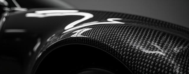 Detail shot of an unpainted carbon fiber fender, highlighting the precise material alignment and smooth, ready-to-paint surface.
