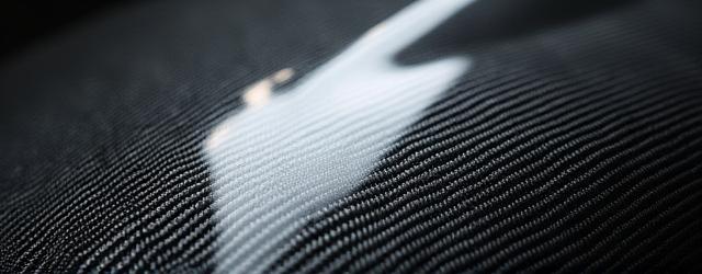 Close-up of an unpainted carbon fiber automotive hood, showcasing perfect weave pattern and a high-gloss, flawless surface ready for paint.